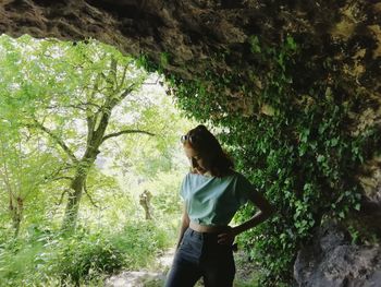 Woman standing by tree in forest