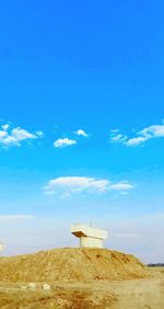 Windmill on field against blue sky