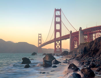 Low angle view of golden gate bridge over river against sky during sunset