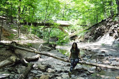 Woman standing on rock by river in forest