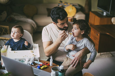 Father feeding son at table in living room