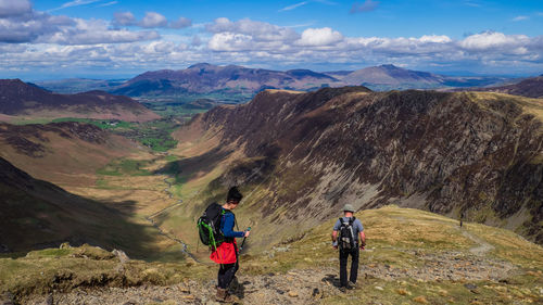 Rear view of men walking on mountain against sky