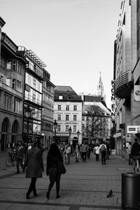 People walking on street in city against clear sky