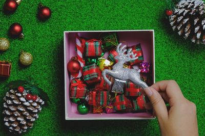 Cropped hand holding christmas decorations on table