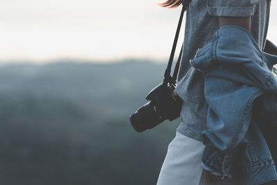 Midsection of woman with digital camera standing outdoors