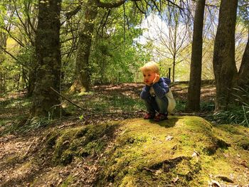 Full length of smiling boy in forest against sky