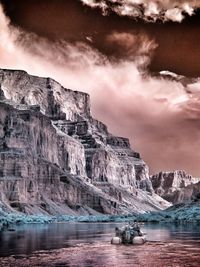 Scenic view of sea by mountain against sky