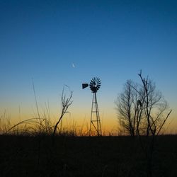 Silhouette of windmill on field against clear sky during sunset