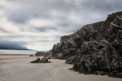 Rock formations on beach against sky