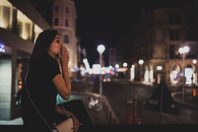 Woman looking at illuminated city at night