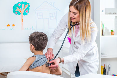 Female doctor examining boy at clinic