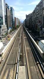 Railroad tracks in city against sky