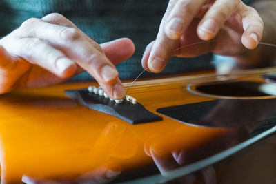 Midsection of man fixing guitar strings