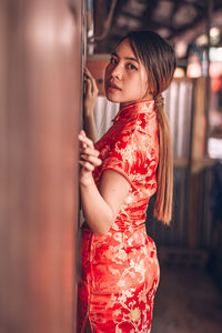 Young woman looking away while standing at home