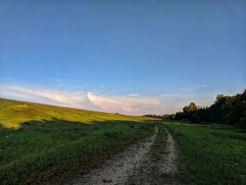 Road amidst field against sky