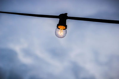 Low angle view of illuminated light bulb against sky