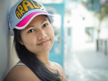 Portrait of smiling woman wearing cap leaning on wall