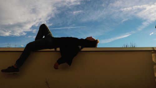 Low angle view of man jumping against sky