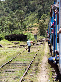 Rear view of people walking on railroad track