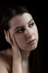 Close-up portrait of a young woman over black background