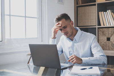 Depressed businessman using laptop in office