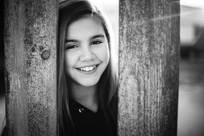 Portrait of smiling girl by wooden fence