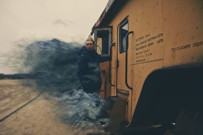 Side view of man standing against the wall