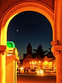 Illuminated street amidst buildings in city at night