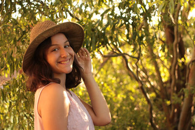 Portrait of smiling young woman against trees