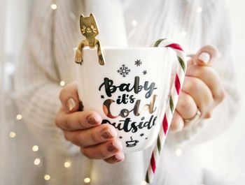 Midsection of woman holding cup during christmas