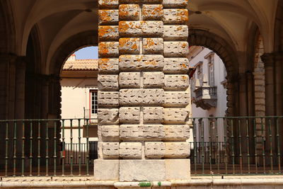 Detail of stone column in front of a stone arch with traditional portuguese houses behind.