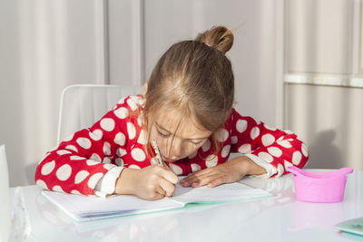 Portrait of girl sitting on table at home