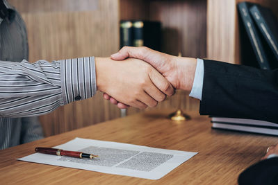 Business people doing handshake over desk in office