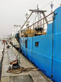 Ship moored at harbor against sky