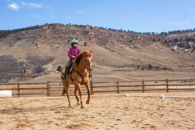 Girl practicing horseback riding in outdoor arena