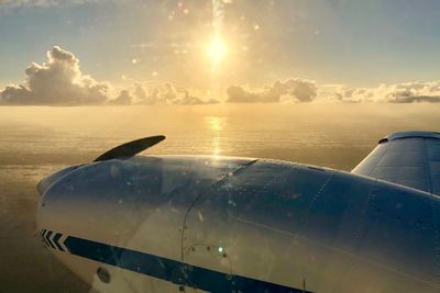 Close-up of airplane wing over sea against sky