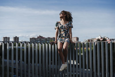 Young woman sitting on railing looking away