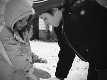 Close-up of siblings on field during snowfall