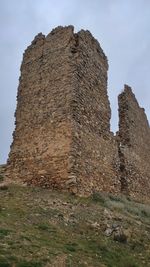 Low angle view of old ruin on field against sky