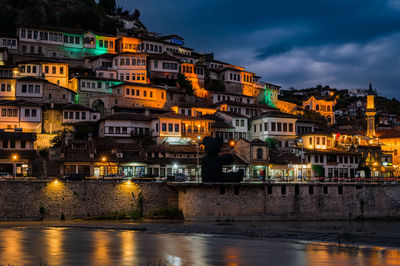 Buildings by river against sky