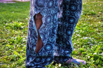 Close-up of man wearing torn pants while standing on land