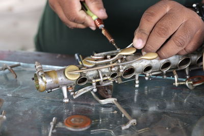 Midsection of man repairing musical instrument in workshop