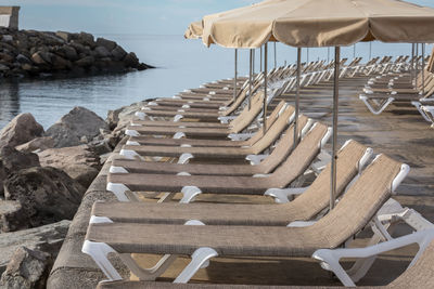 Row of chairs at beach against sky