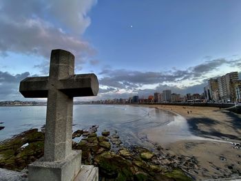 Cross amidst buildings against sky