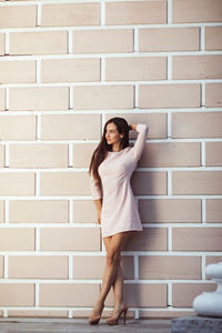 Beautiful young woman against white brick wall