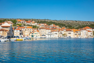 Townscape by sea against clear blue sky