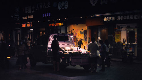 People on illuminated street in city at night
