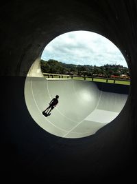 Full length of teenage boy riding push scooter at skateboard park