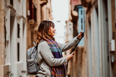 Side view of woman holding monopod standing in alley