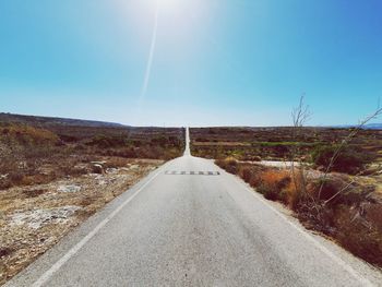 Road amidst land against clear sky